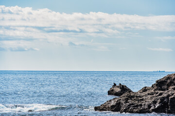 Lonely man fishing in the ocean. Dramatic rock formations on the coast of Pacific Ocean in Nachikatsuura, Wakayama, Japan, part of the Yoshino-Kumano National Park and Nanki Kumano geopark.