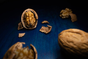Comida. Nuez Chandler sin mitad de cascara entre nueces, sobre mesa azul.