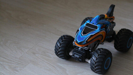 A red and blue monster truck stands on the floor. A car in the shape of a shark. Toy for boy, children. Toy transport for children