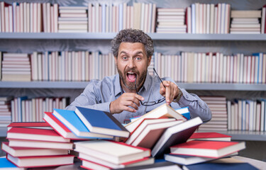 teacher genius in school library. genius studying homework literature near pile of books. man teacher read book. school education in college. knowledge day. overwork of bookworm. got an idea