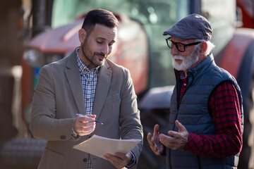 Bank agent talking to farmer on farm about contract