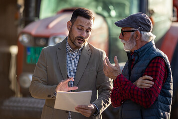 Bank agent talking to farmer on farm about contract © Budimir Jevtic