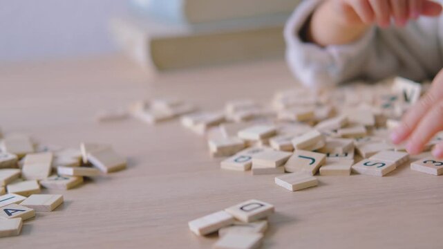 hands close-up, small child 3 years old plays wooden alphabet blocks, makes up words from letters, dyslexia awareness, learning difficulties, human brain development, happy childhood, selective focus
