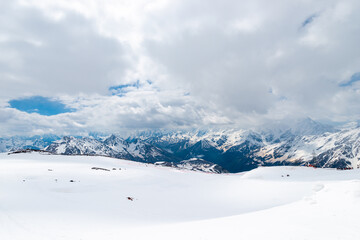 Fototapeta premium A picturesque view of the rocky white peaks of the mountains of the North Caucasus range from the snow-covered slope of Mount Elbrus. Caucasus.