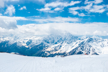 A picturesque view of the rocky white peaks of the mountains of the North Caucasus range from the snow-covered slope of Mount Elbrus. Caucasus