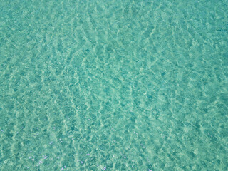 Aerial view of crystal clear turquoise water in Sithonia, Greece, showcasing the mesmerizing patterns and vibrant color of the sea, perfect for backgrounds and nature-themed visuals