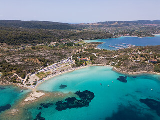 Naklejka premium Aerial view of an island on Sithonia Peninsula, Greece, with beaches and rocks, surrounded by crystal-clear waters. Yachts and boats anchor in turquoise waters. Nearby islets and reefs visible