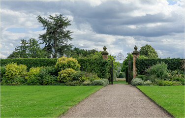 Looking up a pathway towards a hedge and gateway