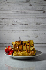 Photography of traditional crepes accompanied by fresh strawberries and blancmange. The colorful presentation highlights freshness and flavor, perfect for recipe blogs and cooking magazines.