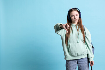 Frustrated woman showing thumbs down sign gesturing, disapproving and offering negative feedback. Disappointed girl doing dislike hand gesture, isolated over studio background