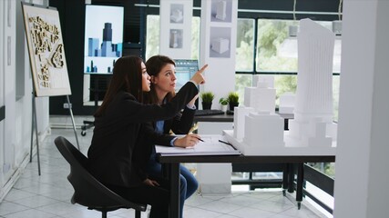 Realty business staff develop architectural schematics using 3D building representation of the original location. Engineers working at startup firm to design a new residential area. Tripod shot.