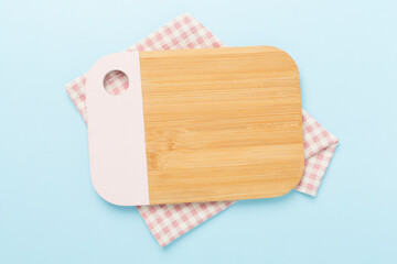 Cutting board with napkin on color background, top view