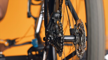 Close up shot of bicycle wheel mechanism being examined by woman during performance assessment. Focus on bike components tested by professional in blurry background ensuring proper function