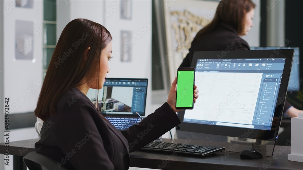 Poster engineer showing phone with greenscreen template on display, working at a architectural agency offic
