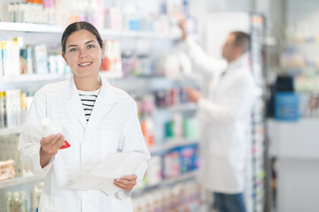 Young female pharmacist in medical uniform posing while working in pharmacy