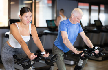 Young athletic woman in sportswear training on exercise bike in gym