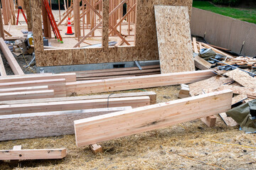 New home construction job site with newly delivered glue laminate beams, house wood framing started
