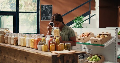 Vegan buyer looking at pasta types in recyclable jars, examining additives free natural bulk items. Woman shopping for organic bio goods, sustainable lifestyle and healthy nutrition. Handheld shot.