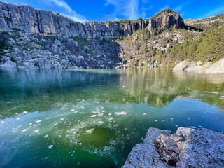 Urbion Black Lagoon with its greenish, icy waters, the ice broken by a stone in the foreground and...
