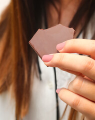 A woman is holding a piece of chocolate in her hand