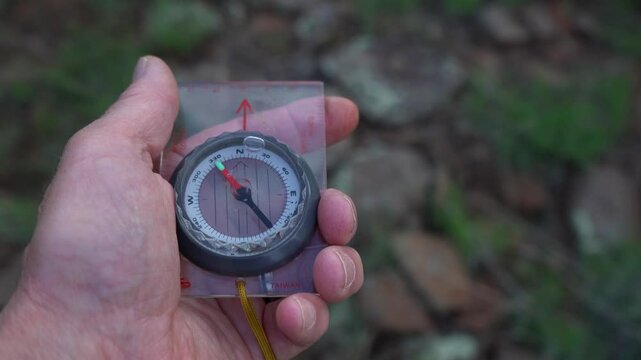 A hiker using a compass to find north in the forest