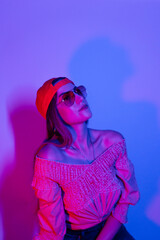 High Fashion model woman in colorful bright neon blue and purple lights posing in studio. woman blowing gum