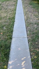narrow cement footpath across a grassy lawn at the park
