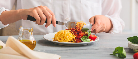 Woman eating tasty pasta bolognese at table, closeup