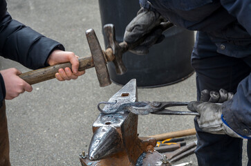 Skilled blacksmith using a hammer and anvil to shape metal engaged in metalworking. Traditional...