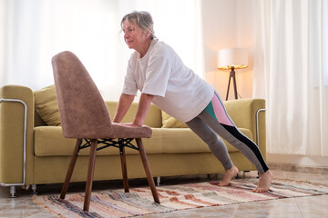 Senior caucasian woman doing yoga at home on chair