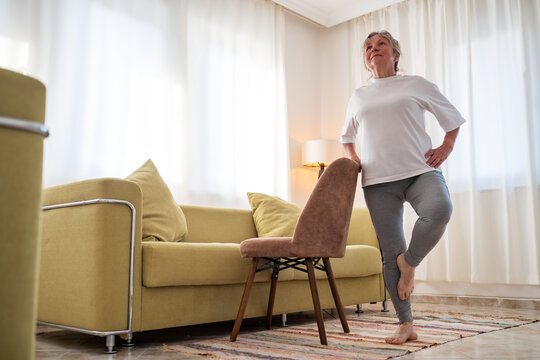Senior caucasian woman doing yoga at home on chair