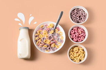 Bowls with colorful sweet cereal rings and bottle of milk on brown background