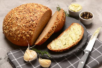 Board of bread slices with fresh butter and different spices on grey background