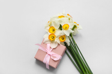 Bouquet of beautiful daffodil flowers and gift box on grey background
