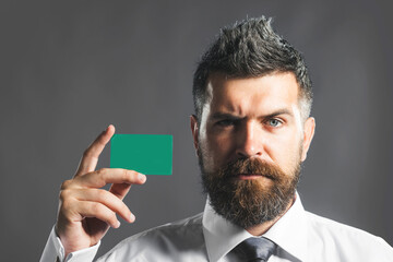 Serious businessman showing credit card. Bearded business man advertising banking services, loan or deposits, cashback for purchases. Handsome male with empty visiting card, credit debit card mockup.