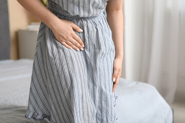 Young woman suffering from cystitis in bedroom, closeup
