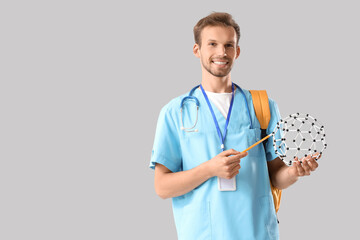 Male medical intern with molecular model on light background