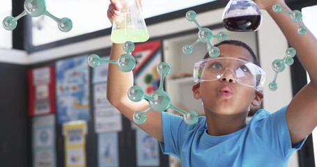 Conducting science experiment, child holding beakers with molecular structure image