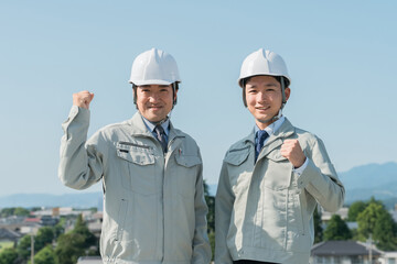 青空の中に立つ作業服を着た作業員（建設・建築・設計・不動産・土木・工事・現場監督・運送）
