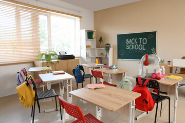 Interior of empty classroom with chalkboard, desks and backpacks