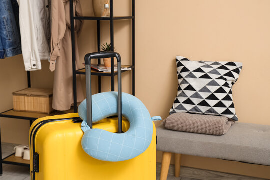 Yellow suitcase and neck pillow in hall. Travel concept