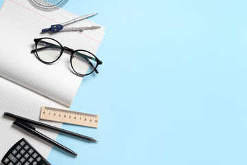 Open copybook with blank pages and stationery on blue background