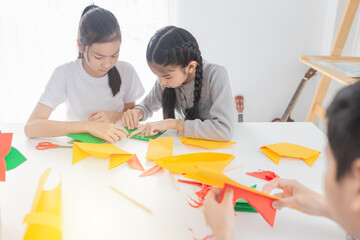 asian children group learning to folding paper in art origami time, they feeling fun and happy, child imagine and development