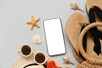 Mobile phone and beach accessories with flip-flops on grey background. Top view