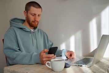 man with a phone working on laptop