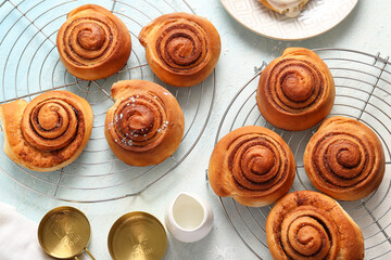 Stands with sweet cinnamon rolls and jug of milk on light blue background