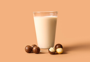 Glass of fresh macadamia milk on brown background