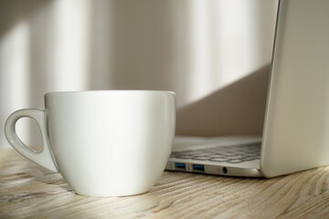 White cup of coffee on the table and laptop