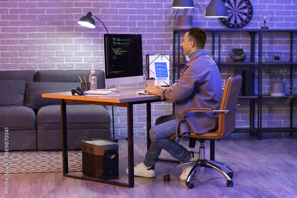 Poster male programmer working with computer in office at night