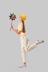 Teenage girl with toy windmill on light background